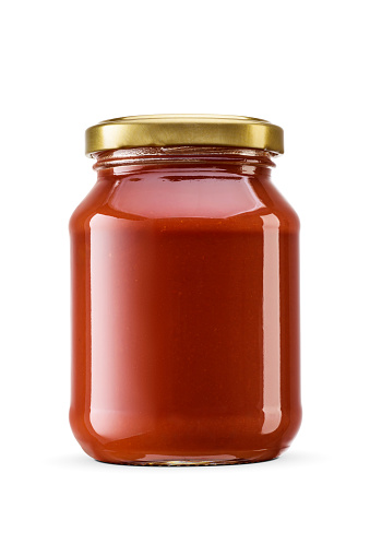 Tomato paste in a transparent glass jar isolated on white background with clipping path.