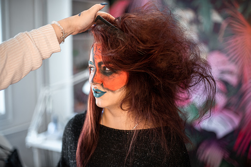 Young woman getting her hair done for Halloween party, hair tousling