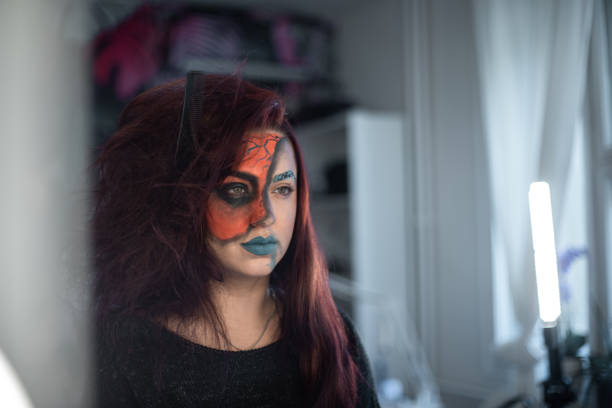 Young woman with artistic make-up looking at the mirror and laughing