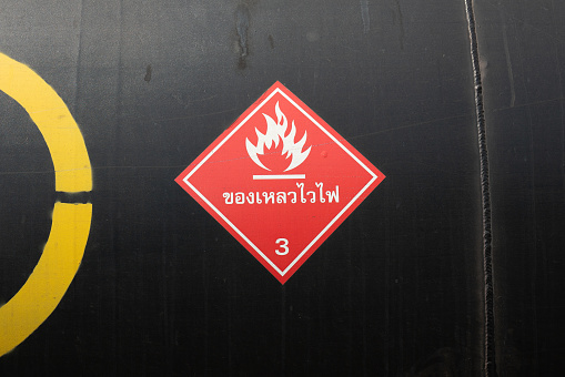 Caution sign of the Flammable liquid (in Thai langauge) on red placard that placed on the crude oil storage tank for transportation on the train cargo. Industrial safety sign and symbol.