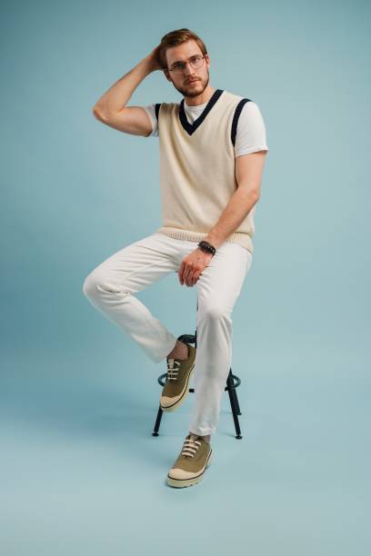 istock Feeling comfortable. Joyful positive young man sitting on a stool and smiling isolated on blue 1990299675