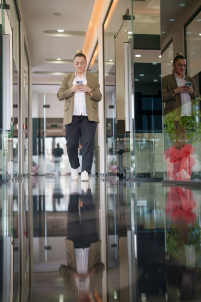 istock Pregnant woman using mobile phone in hallway at work 1990321581