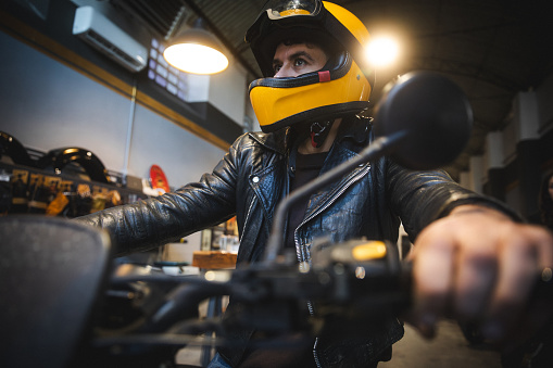 Portrait of man wearing helmet and motorcycle indoor in motor shop