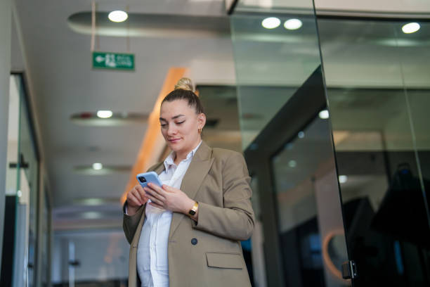 istock Pregnant woman using mobile phone in hallway at work 1990330349