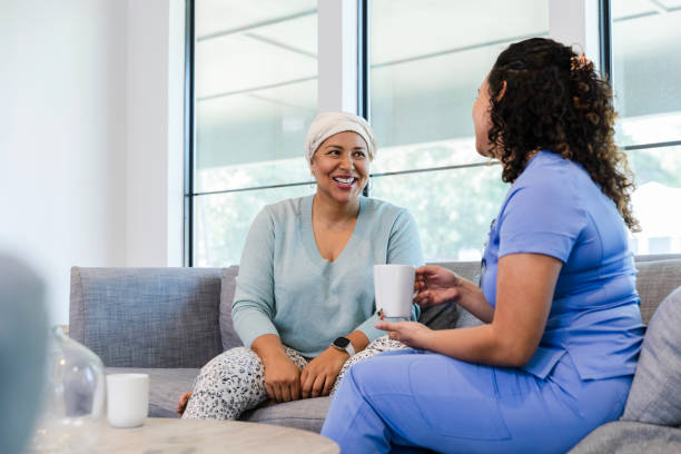 istock Female hospice patient and nurse sit on sofa and chat 1990335927