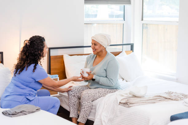 istock Female aide helps cancer patient with hot drink 1990336484