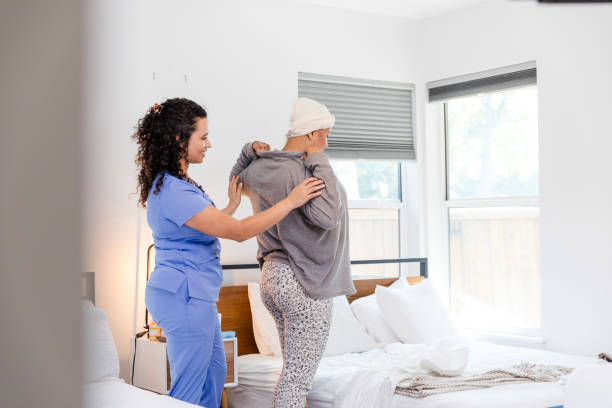 istock Female cancer patient dons sweater with female nurse's help 1990336516
