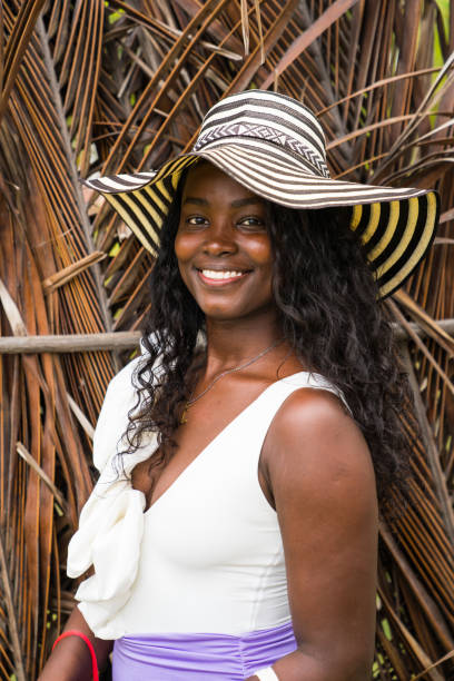 In this captivating image, we see a radiant African American woman, approximately 25 years old, exuding a vibrant and youthful energy. She is gracefully posing on a sandy beach, with the stunning backdrop of the ocean enhancing her natural beauty. Dressed in a stylish white swimsuit, she embodies the essence of summer fashion and beachwear.Her confident pose and charming smile are the epitomes of casual elegance. The sunlit setting casts a warm, sun-kissed glow on her radiant skin, highlighting her effortless beauty. She looks both carefree and trendy, perfectly encapsulating a modern, healthy lifestyle.This beach photoshoot captures more than just a fashionable moment; it's a celebration of joy, relaxation, and positive energy. The outdoor photography showcases her as not just a female model, but a symbol of contemporary, coastal chic. Her presence is both alluring and inspirational, making the image not only photogenic but also full of life and energy.