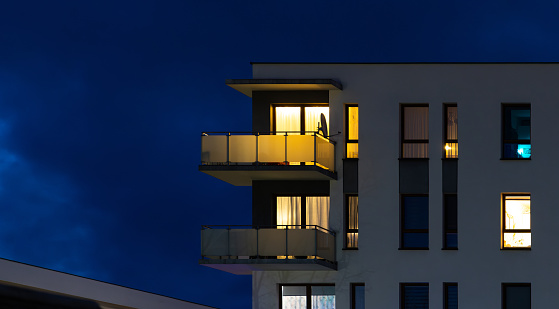 The facade of a white residential building against the night sky.