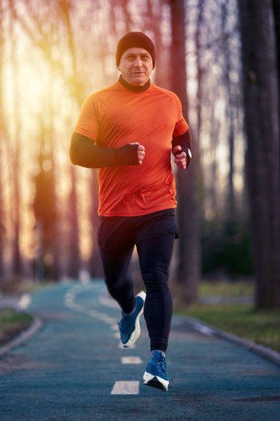 Athletic man joggin in park at sunset in a cold winter day