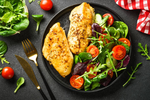 Green salad with chicken fillet on black. Fresh salad with chicken fillet and vegetables on black. Healthy food, keto diet. paleo diet stock pictures, royalty-free photos & images