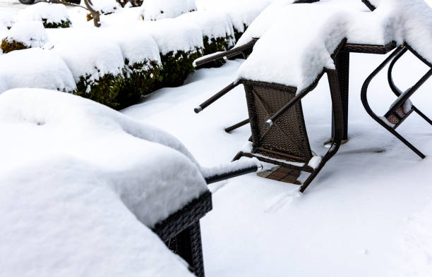 istock Plastic chairs and a garden table covered with a thick layer of snow. 1990356219
