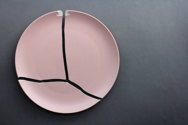 istock A broken pink ceramic plate on a gray background. view from above. The concept of diet, old things 1990365853