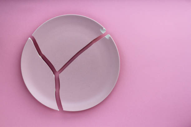 istock A broken pink ceramic plate on a gray background. view from above. The concept of diet, old things 1990366377