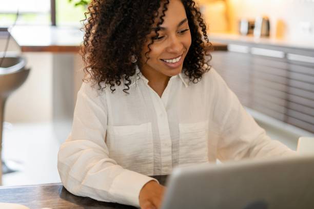 istock Smiling young black woman freelancer working from home, using laptop, copy space. Relaxed african american lady enjoying her weekend, surfing on internet on laptop 1990366925