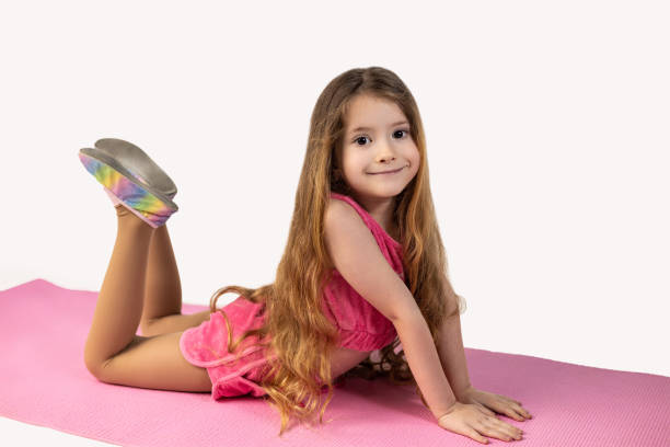 istock Cute little girl practicing yoga on mat against white background 1990376507