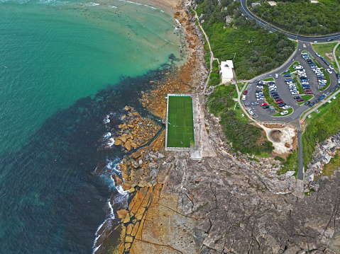 An aerial view of Freshwater Rockpool with parked cars on the green shore. Australia