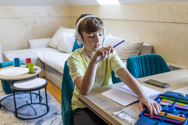 istock Schoolboy is chatting online with his classmates while doing his homework at the kitchen dining table. 1990385686