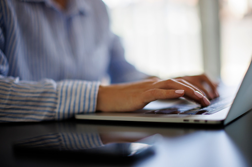 Closeup of businesswoman using laptop and typing