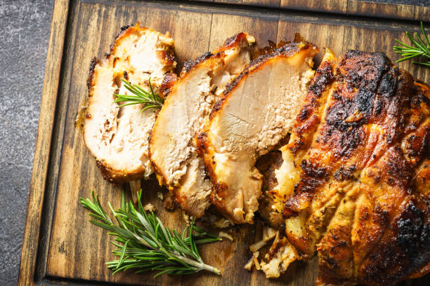 istock Roasted pork with herbs on wooden cutting board. 1990415850