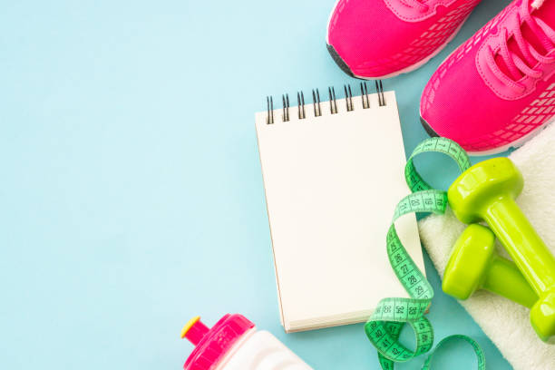 istock Dumbbells, sneakers, measuring tape, water bottle and notepad on blue. 1990418584