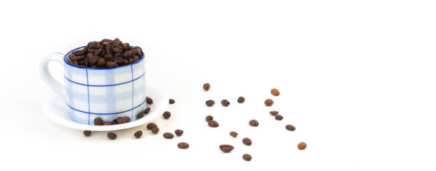 Cup of coffee with roasted coffee beans against a white background, high angle view.
