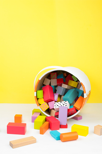 Children's toy, wooden constructor, poured out of a bucket on a yellow background