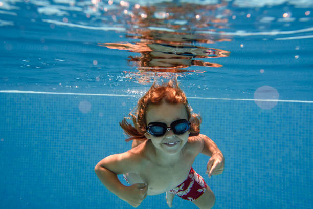 istock Excited boy in goggles swimming in pool 1990441337