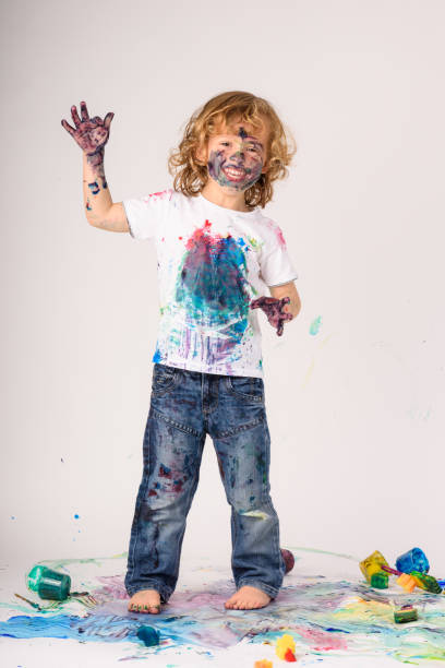 istock Cheerful boy covered with colorful paints 1990446047
