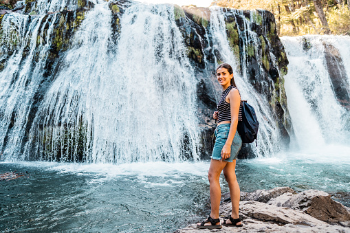 Portrait of a young woman on a waterfall in a Patagonia, Argentina
