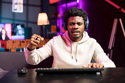 Cheerful gamer feeling excited after finally defeating all enemies while playing on computer. Joyful african american man congratulating himself after winning videogame on gaming PC