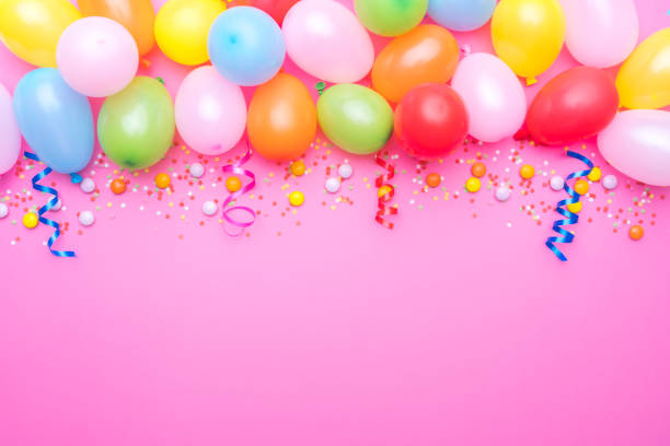 istock Party balloons and confetti border on pink background. Copy space 1990537497