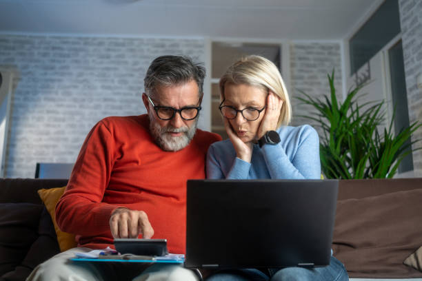 istock Senior couple sitting at the kitchen table looking at digital tablet and recalculating their expenses. 1990548791