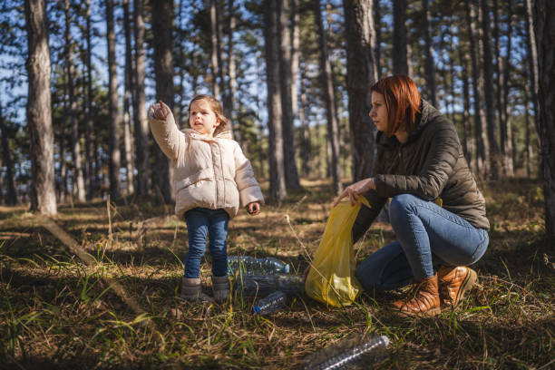 istock mother and daughter collect plastic bottle garbage waste in forest 1990552126
