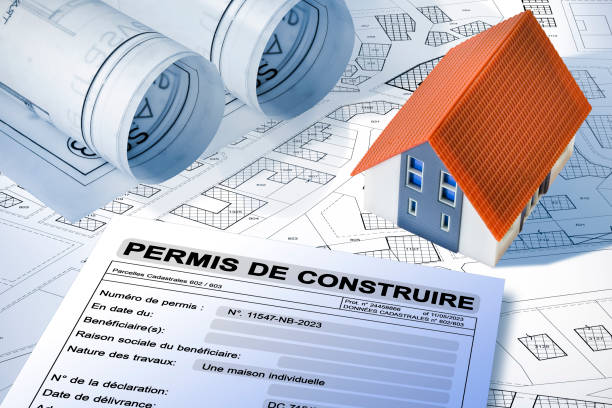 istock Building permit concept written in French - PERMIS DE CONSTRUIRE - Building activity and construction industry with imaginary cadastral map and home model 1990567405