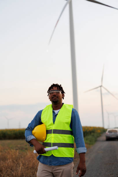 istock Young Engineer wearing uniform ,helmet hold document inspection work in wind turbine farms rotation to generate electricity energy 1990573300