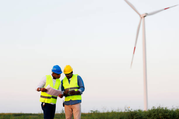 istock Two young Engineers wearing uniform ,helmet hold document inspection work in wind turbine farms rotation to generate electricity energy 1990582150