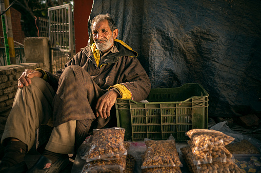 Solan, Himachal Pradesh, India - December 29, 2023: A nomadic man from Kashmir earns his livelihood by selling Kashmiri almonds and walnuts on the streets of Solan, Himachal Pradesh.
