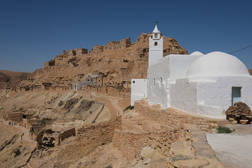 View of a white Mosque at Chenini deserted hilltop old berbere town in tunisia against blue sky. A ruined Berber village in the Tataouine district in southern Tunisia. Located on a hilltop.