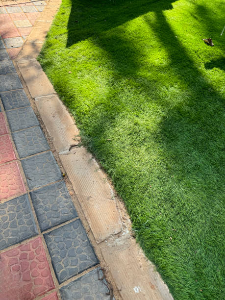istock Full frame image of artificial, green grass lawn by block paved patio with red and black square tiles, lined with terracotta rectangular bricks, elevated view 1990604411