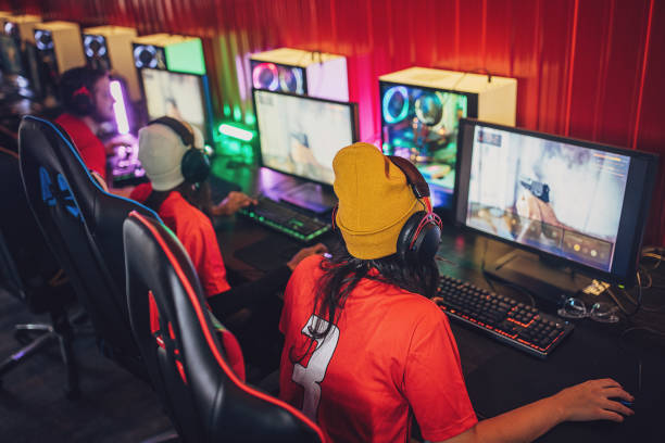 Multiracial group of people, professional cybersport gamers playing video games on esports competition on desktop computers together in gaming club.