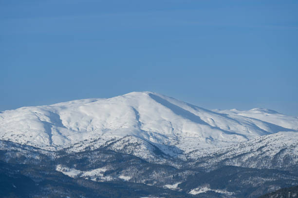 Winter in Stora Sjöfallet National park. The river is frozen and has tracks of snow mobiles. In the background the snow covered mountains. Blue sky.