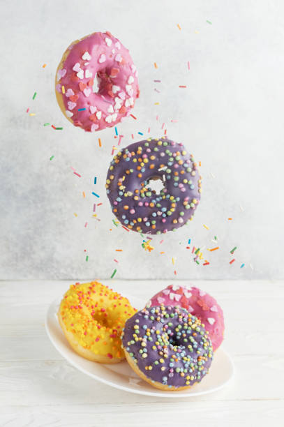 istock Two levitating donuts with sugar sprinkles on a gray background. Sweet donuts on a gray background. 1990616595