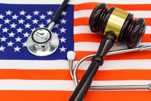 Justice in Healthcare. A gavel and stethoscope on the American flag, symbolizing the intersection of law and healthcare