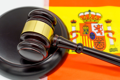 Justice in Spain. A judges gavel rests on the vibrant Spanish flag, symbolizing the countrys legal system