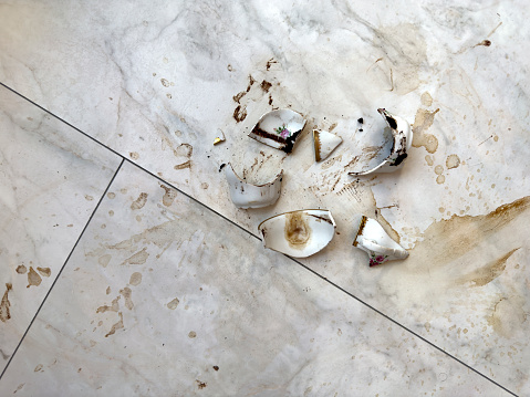 Broken porcelain coffee cup on granite floor of house interior