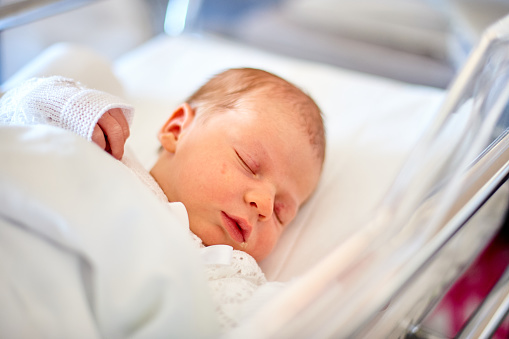 Newborn baby sleeping in its hospital crib