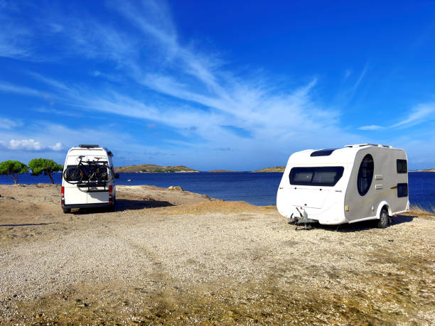 istock Camper van and camper trailer parked at sunny seaside 1990669208