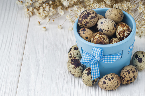 Easter holiday concept with quail eggs in pot on wooden background (selective focus).
