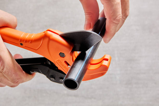 istock Using pipe cutter with ratcheting mechanism when installing sprinkler water line, close-up of cutting plastic pipe. 1990716028